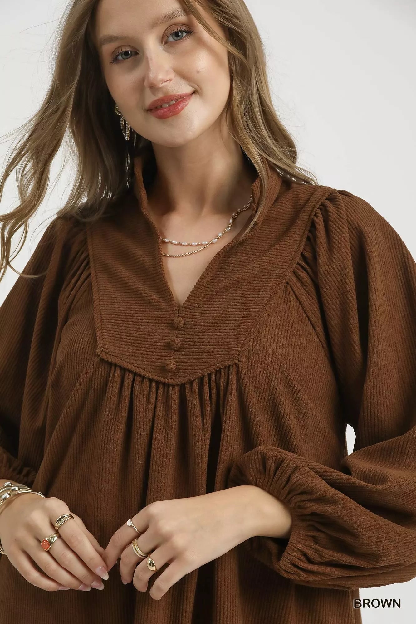 Woman modeling brown corduroy tiered babydoll dress with V-neck and puffed sleeves.