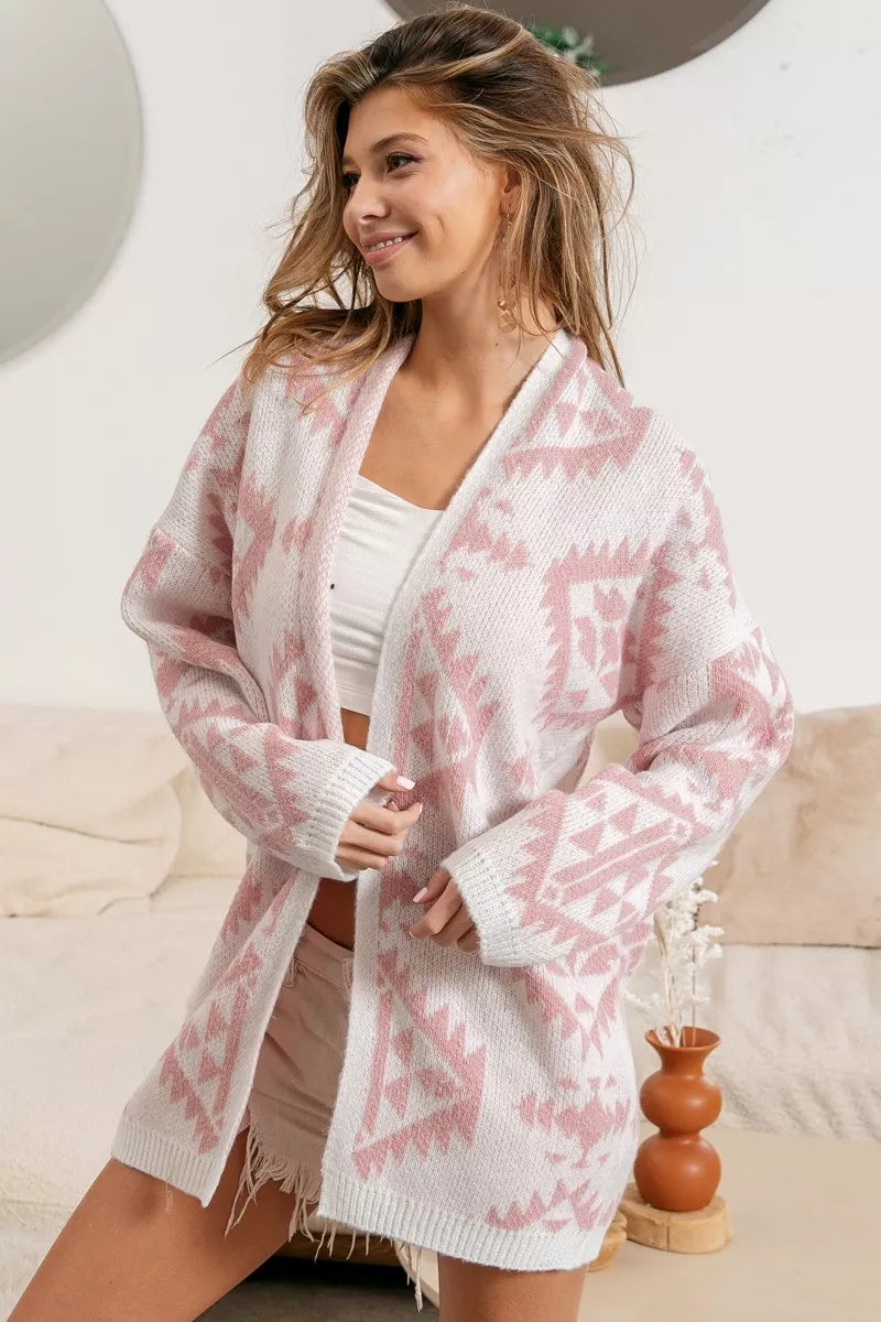 Pink open-front acrylic cardigan with Aztec pattern, modeled by a smiling woman.