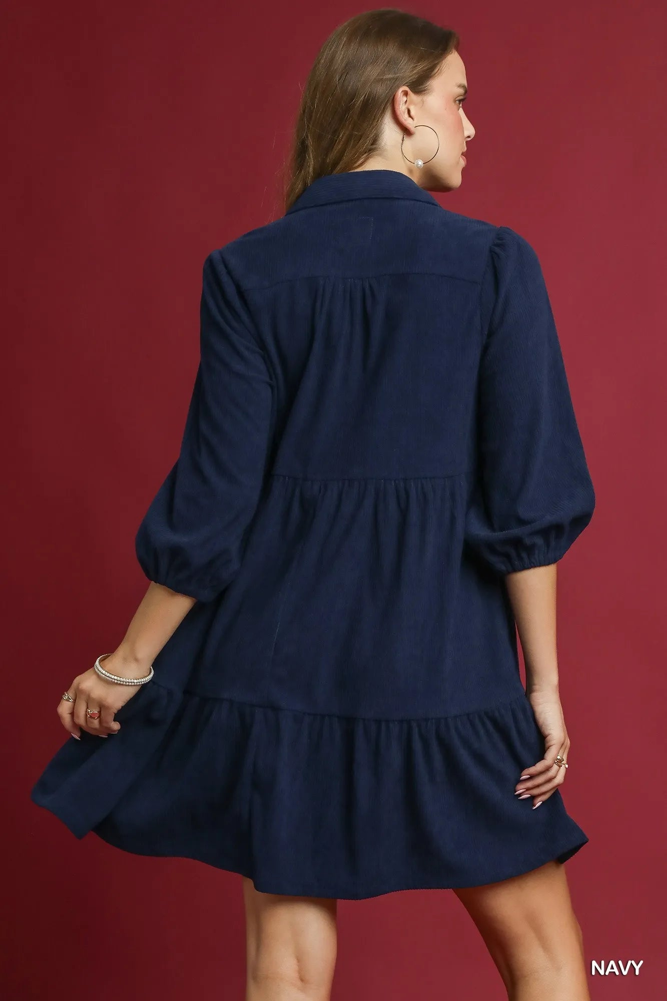 Rear view of navy tiered corduroy mini dress with balloon sleeves on model.