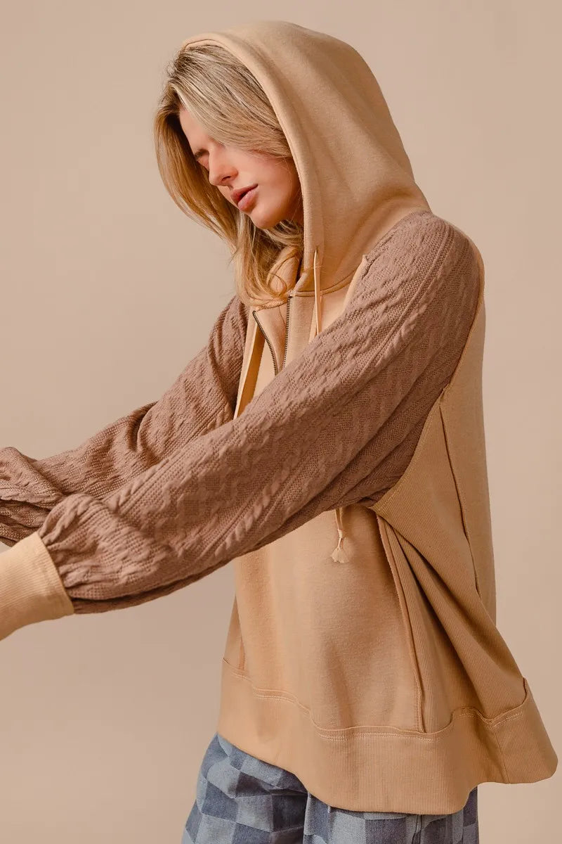 Beige half-zip French terry hoodie with knit sleeves on a model.
