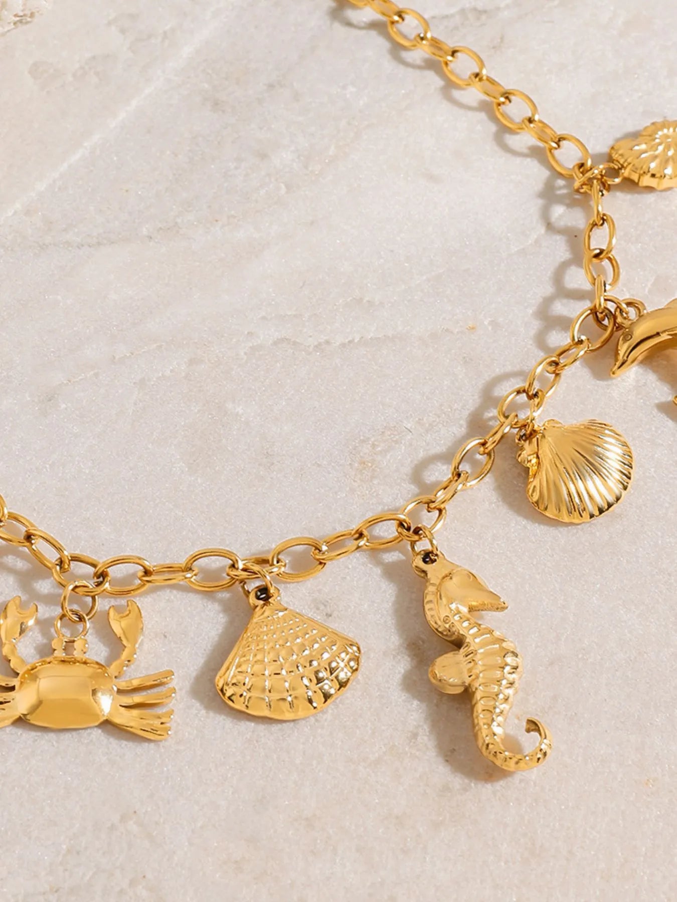 18K gold-plated stainless steel necklace with ocean-themed charms including shells, crabs, and seahorses.
