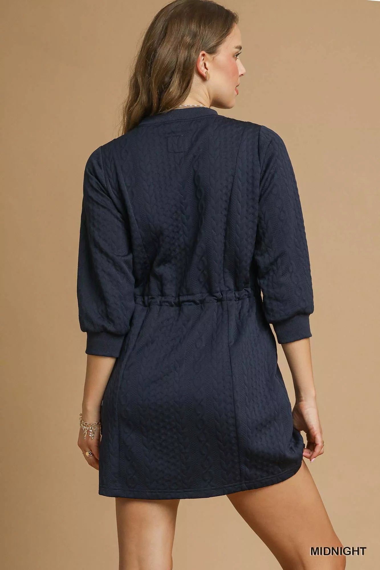 Back view of navy cable knit mini dress with drawstring waist and pockets.