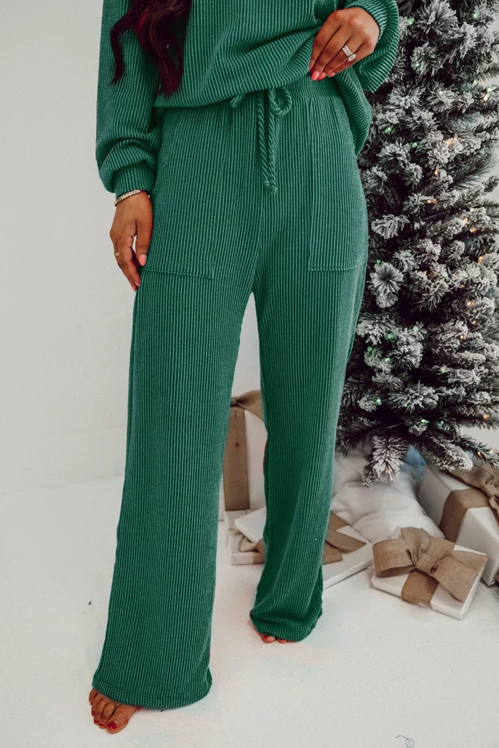 Woman wearing a green polyester top and drawstring pants set in front of a Christmas tree.