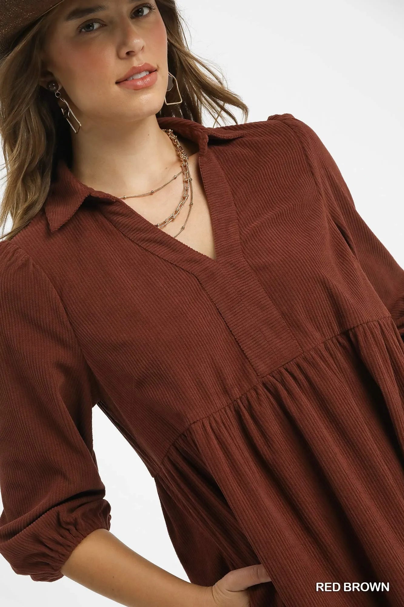 Woman modeling a red-brown corduroy mini dress with tiered skirt and balloon sleeves.