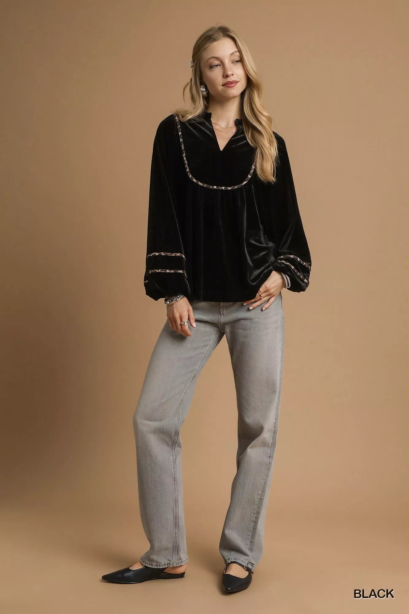 Black velvet long-sleeve blouse with contrast trim on a model.
