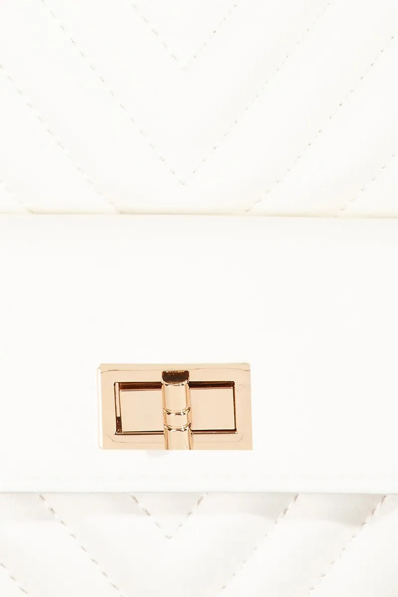 White quilted faux leather sling bag with gold-tone clasp and strap.
