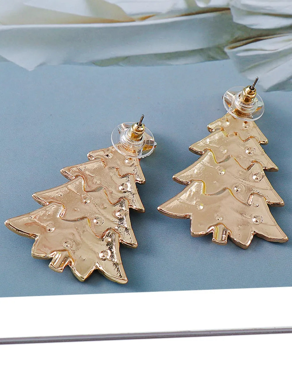 Pair of gold alloy Christmas tree earrings with rhinestone inlays and stud backs.