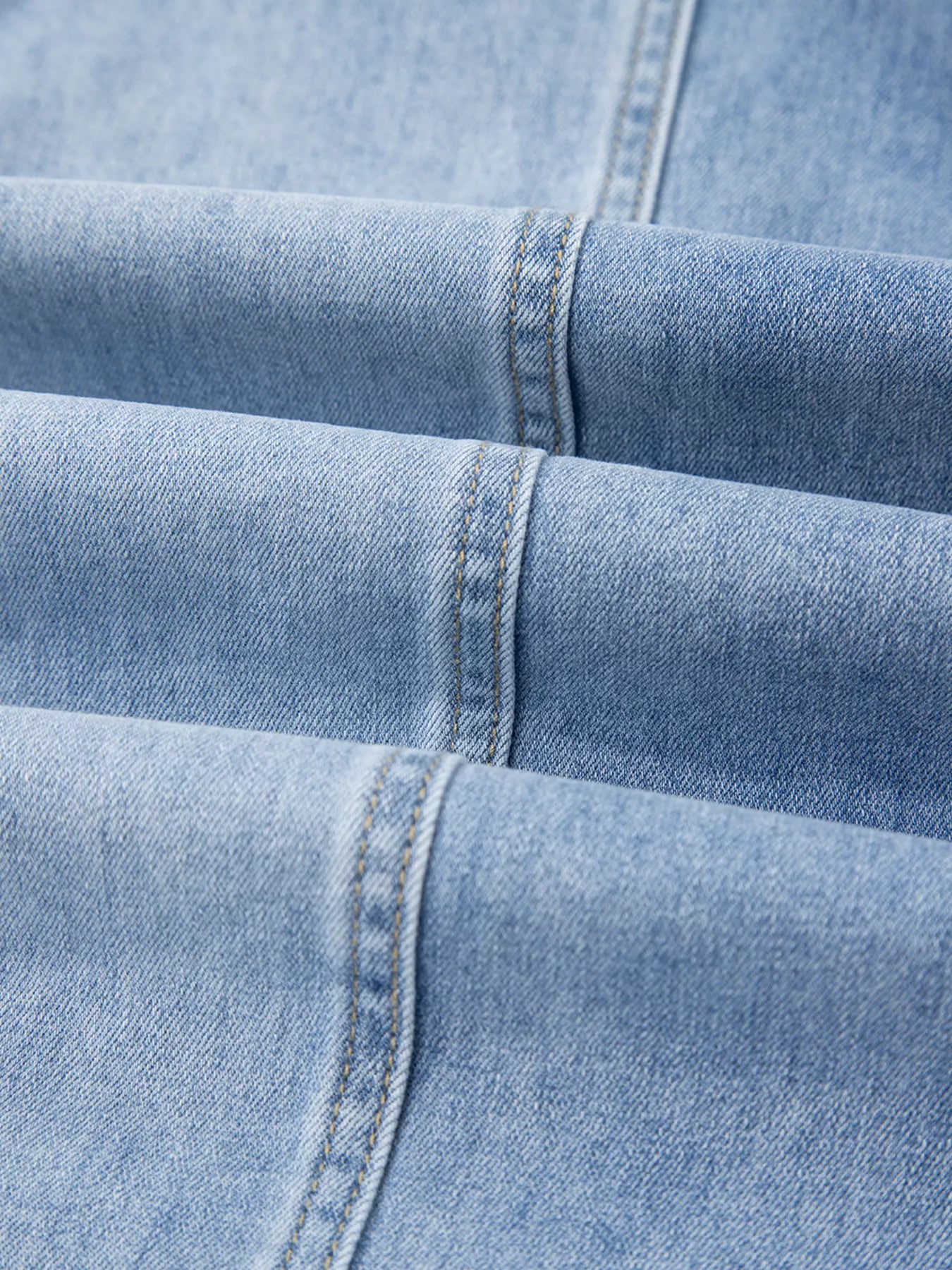 Close-up of light wash wide-leg jeans showing drawstring waist and raw hem.