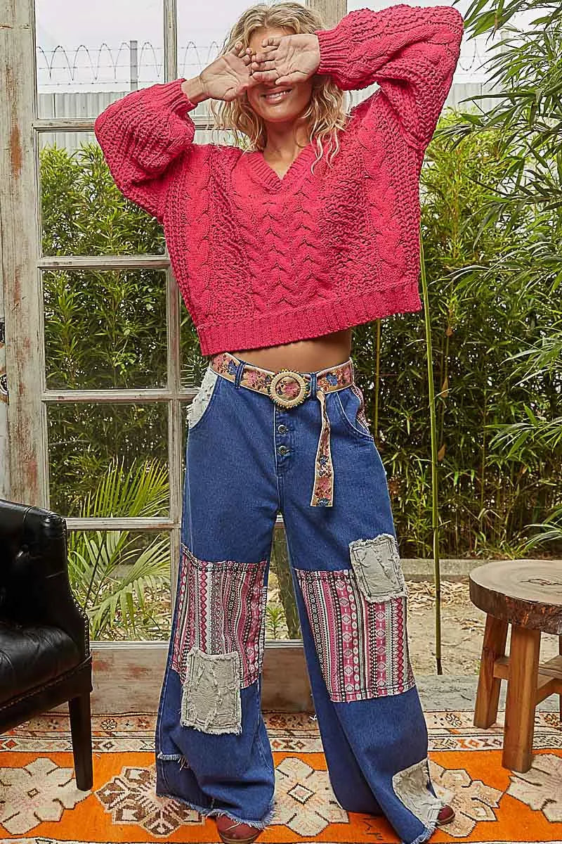 Close-up of model wearing a red cropped V-neck cable-knit chenille sweater with balloon sleeves.