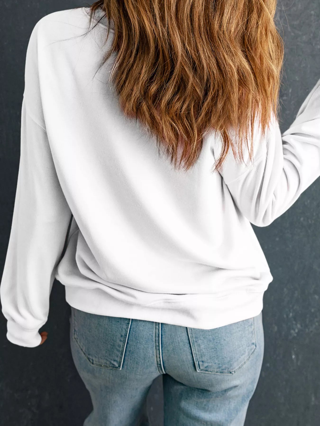 Rear view of white crew neck sweatshirt with leopard rugby graphic on a model in jeans.