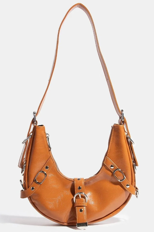 Cognac brown crescent leather shoulder bag with metal buckles and tassels.