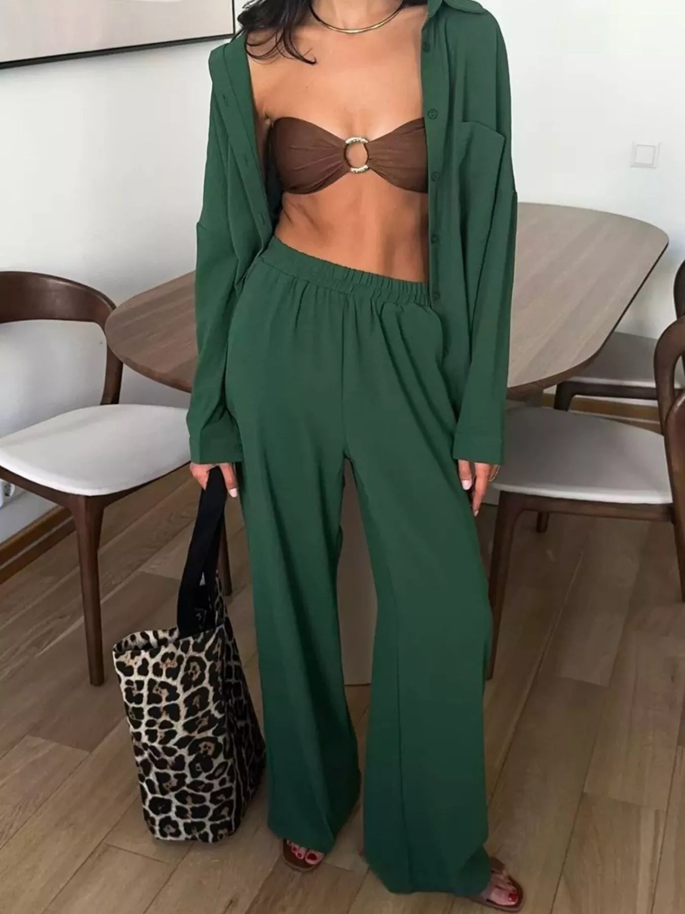 Woman wearing a green two-piece button-down shirt and wide-leg pants set with a brown bralette.