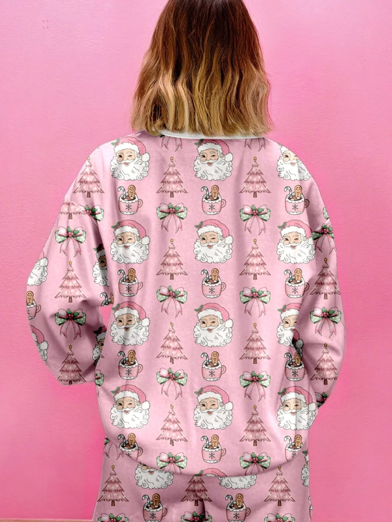 Back view of a woman in a pink two-piece lounge set with festive Santa and Christmas tree print.
