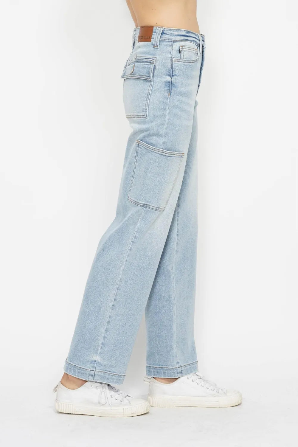 High-waist straight-leg cargo jeans in light wash with multiple pockets, modeled on a person wearing white sneakers.