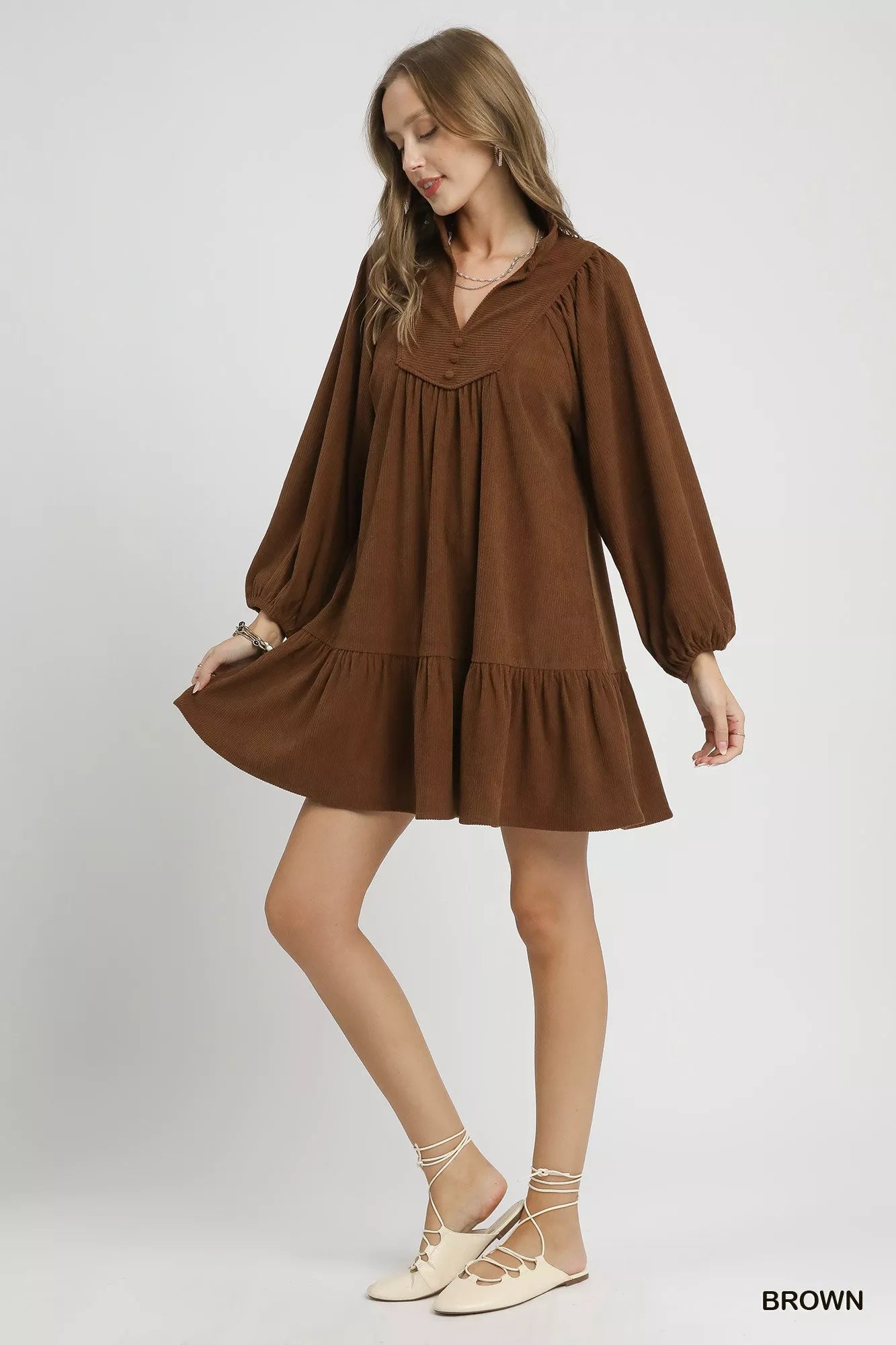 Brown corduroy tiered babydoll dress with V-neck, long sleeves, and ruffled hem.