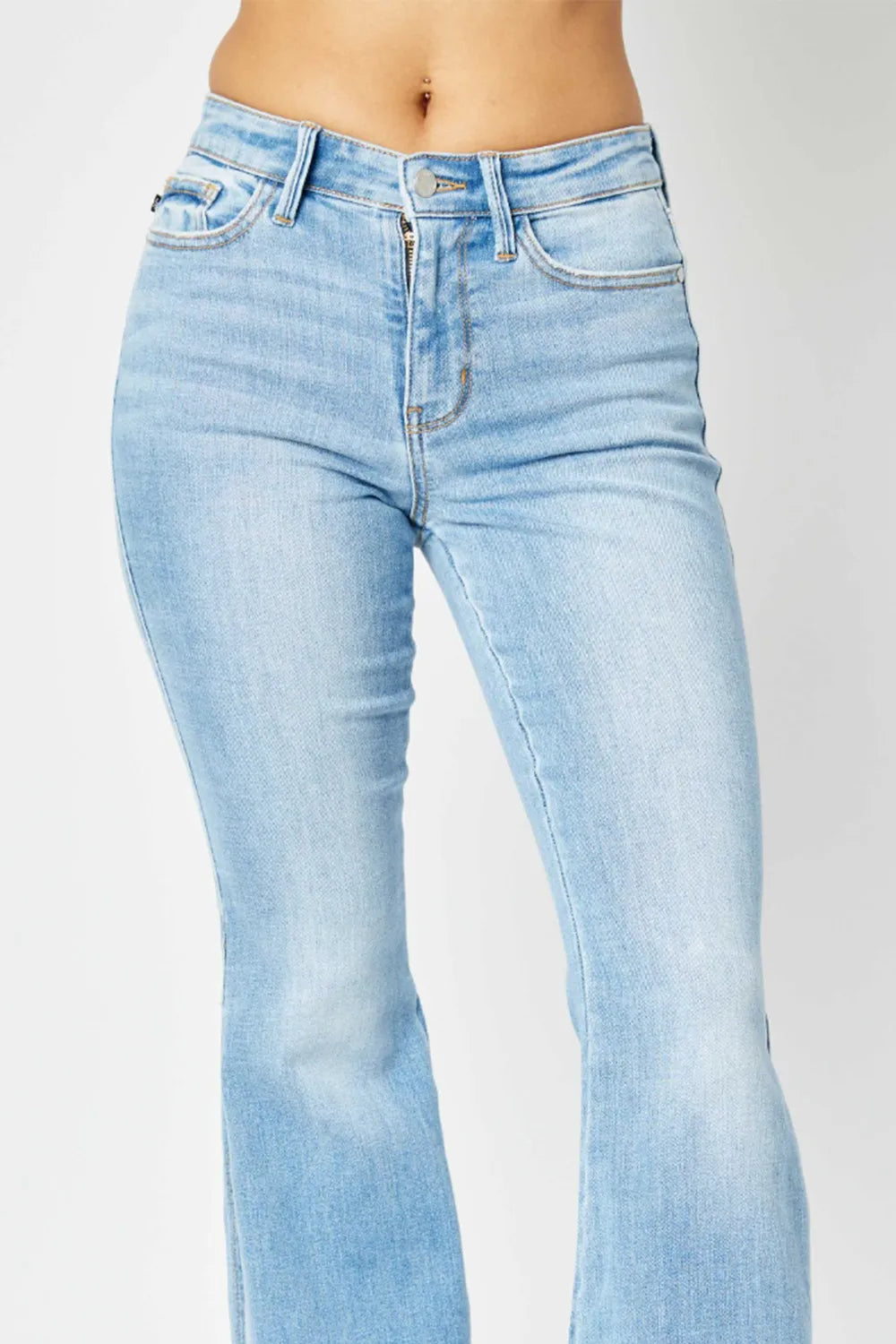 Light wash mid-rise Judy Blue flare jeans with raw hem on a model.