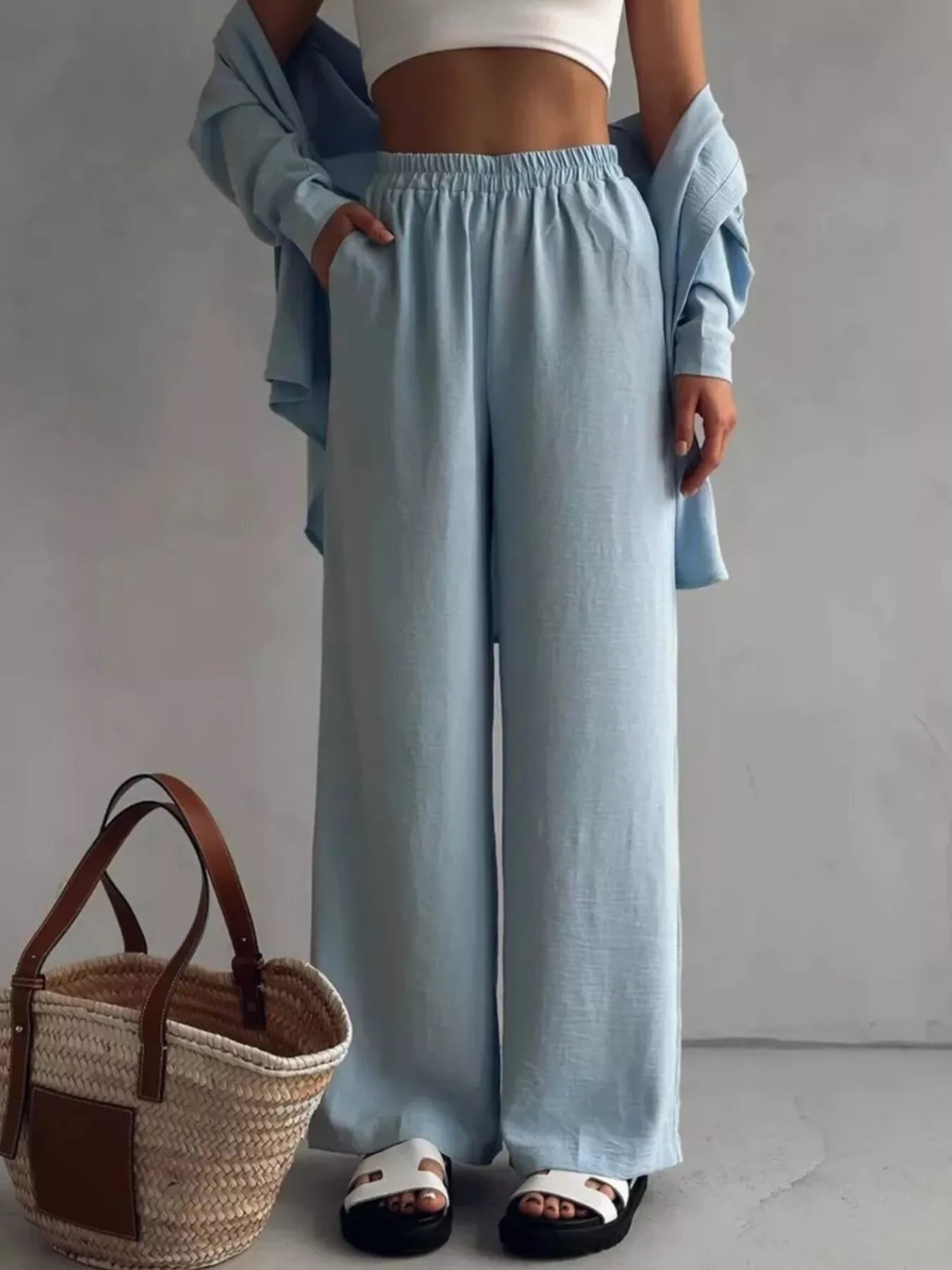 Woman modeling a light blue two-piece set with button-down shirt and wide-leg pants.