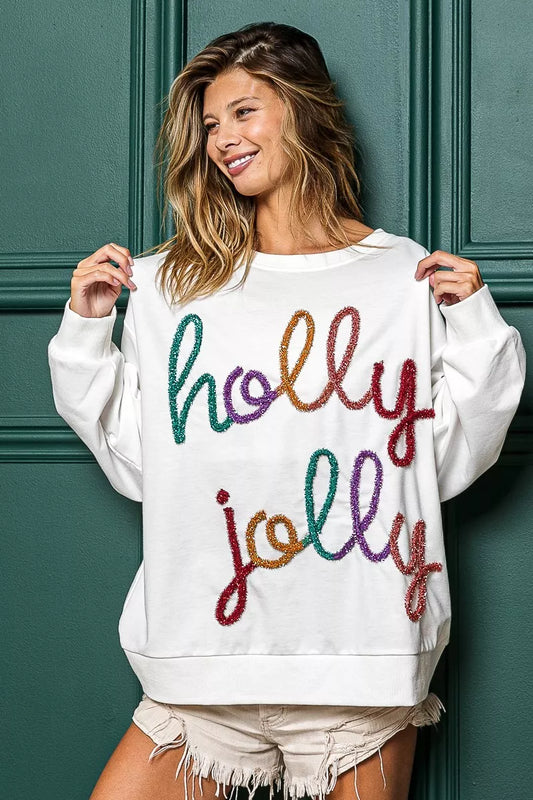 White French terry sweatshirt with colorful "Holly Jolly" text graphic.