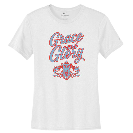 White Nike women's Dri-FIT tee with "Grace & Glory" text and floral emblem in powder blue.