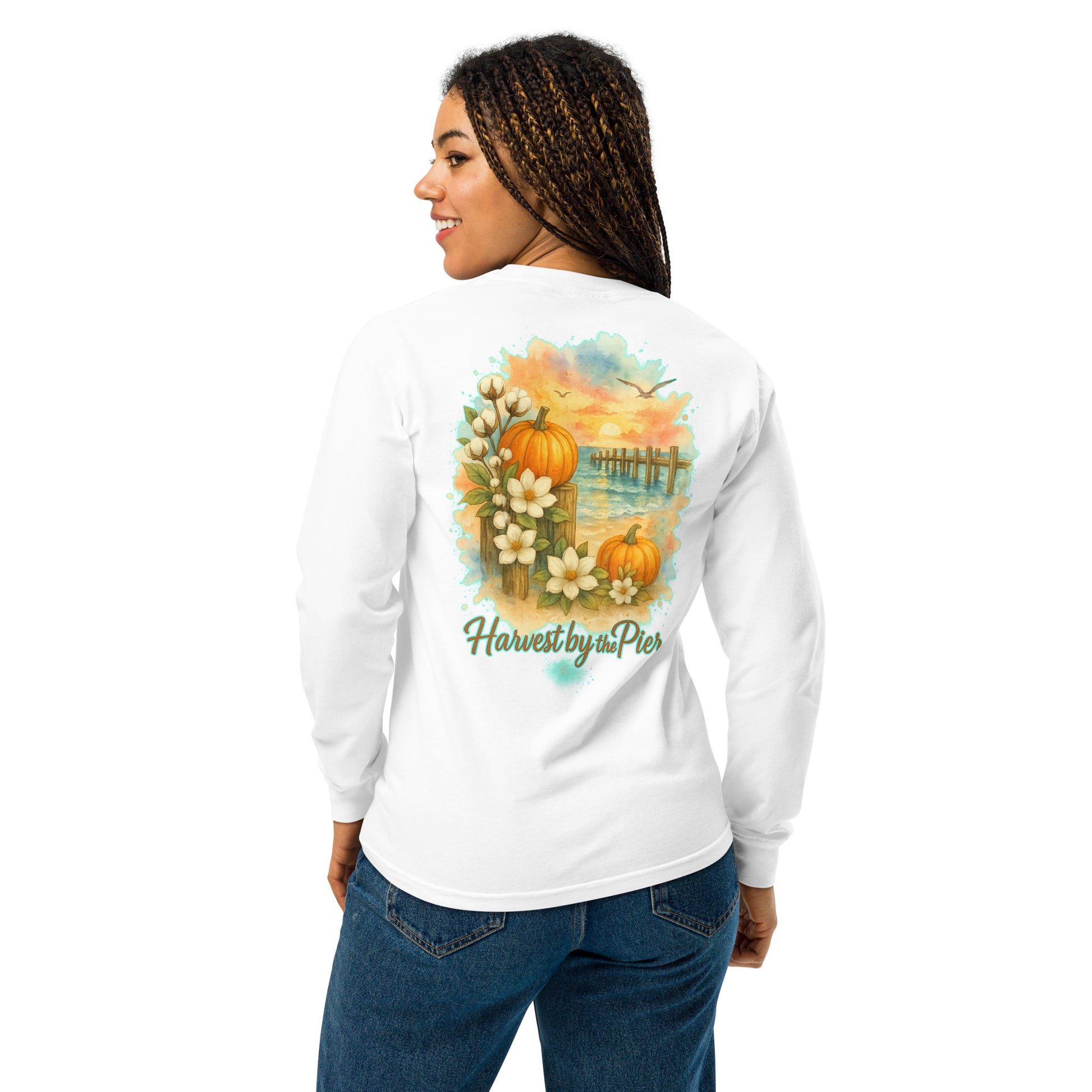 Back view of a white long-sleeve unisex tee on a woman, featuring a pier sunset with pumpkins, palms, and magnolias.