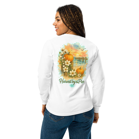 Back view of a white long-sleeve unisex tee on a woman, featuring a pier sunset with pumpkins, palms, and magnolias.