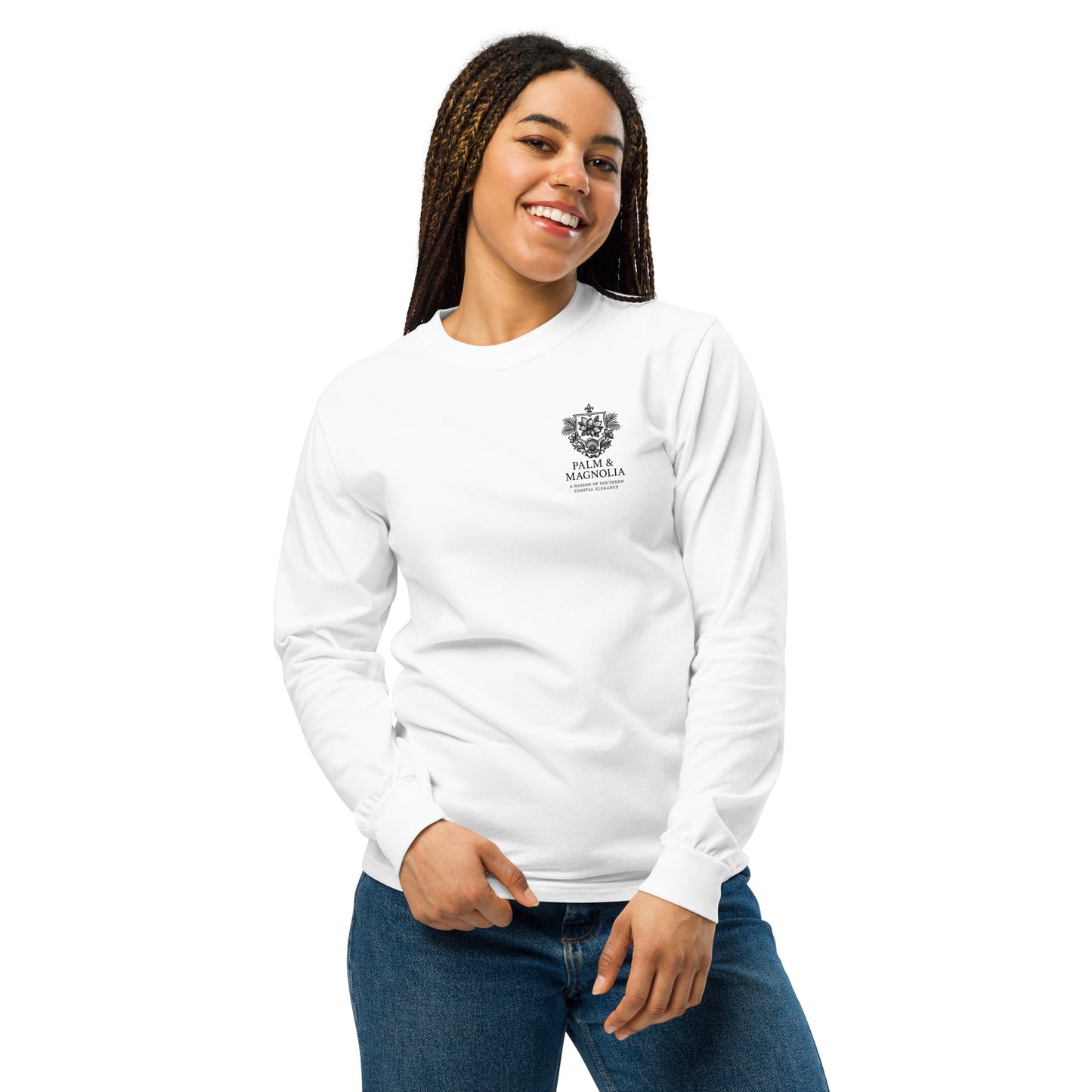 A smiling woman models a white unisex long-sleeve tee with a Harvest by the Pier palm and magnolia print on the chest.