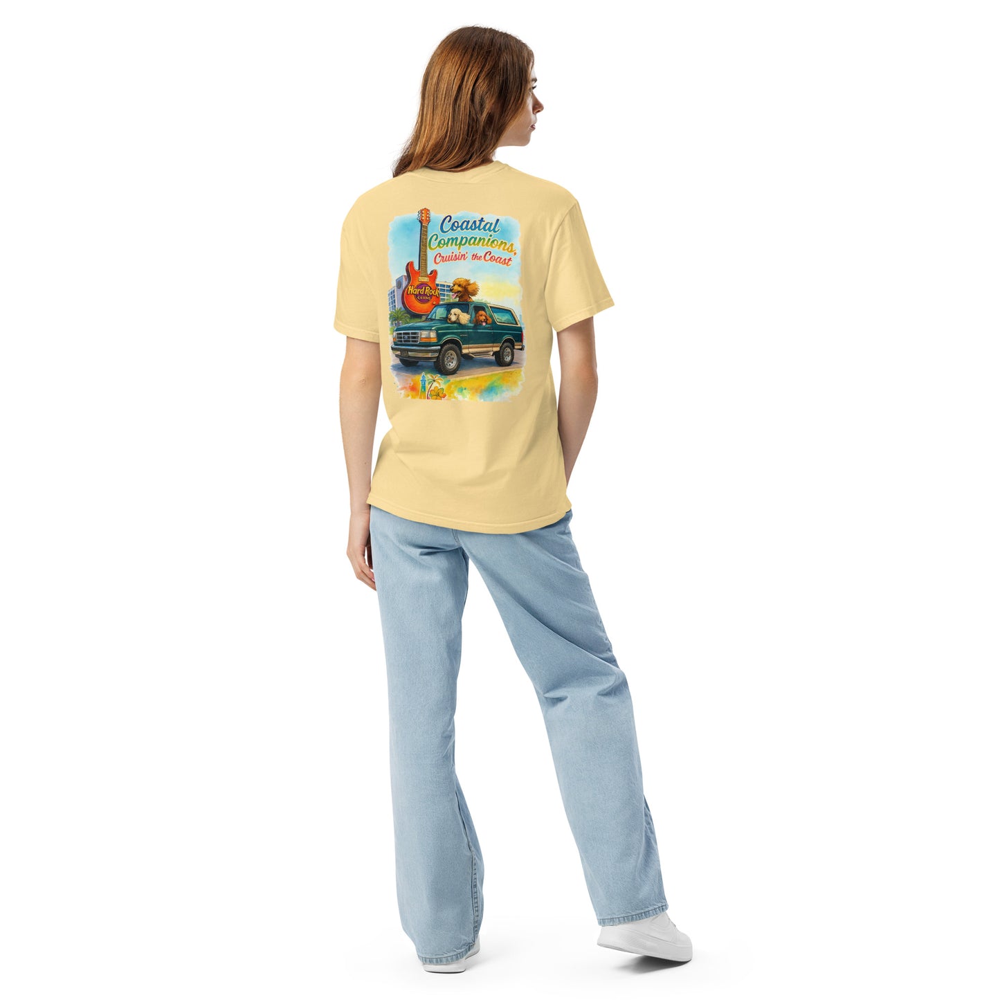 Back view of a woman wearing a yellow Comfort Colors tee with a coastal design of a green Bronco, dogs, and Hard Rock guitar.