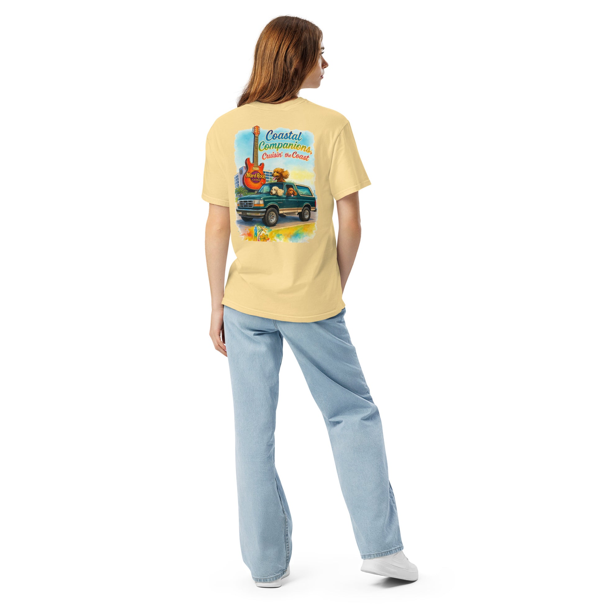 Back view of a woman wearing a yellow Comfort Colors tee with a coastal design of a green Bronco, dogs, and Hard Rock guitar.