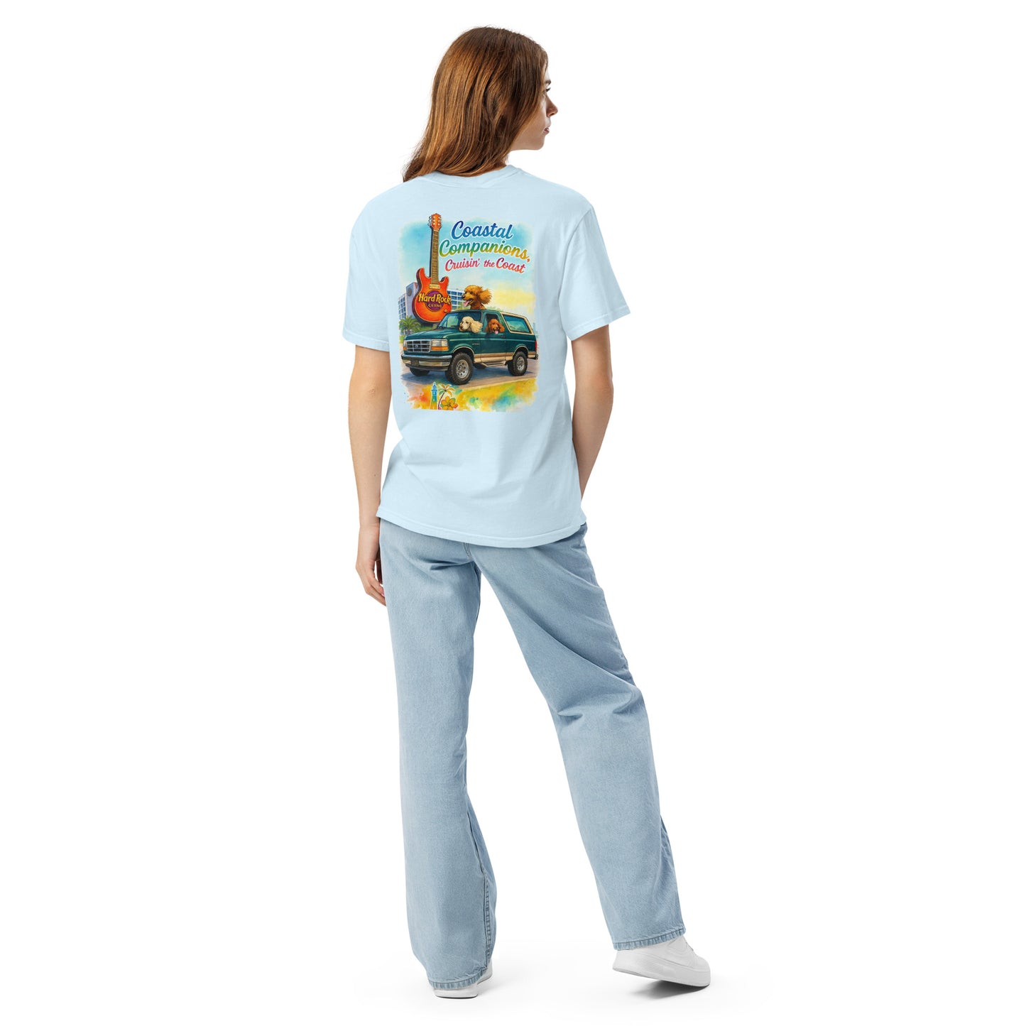 Back view of a light blue Comfort Colors tee on a model, featuring a coastal design with a green Bronco, guitar, and dog.