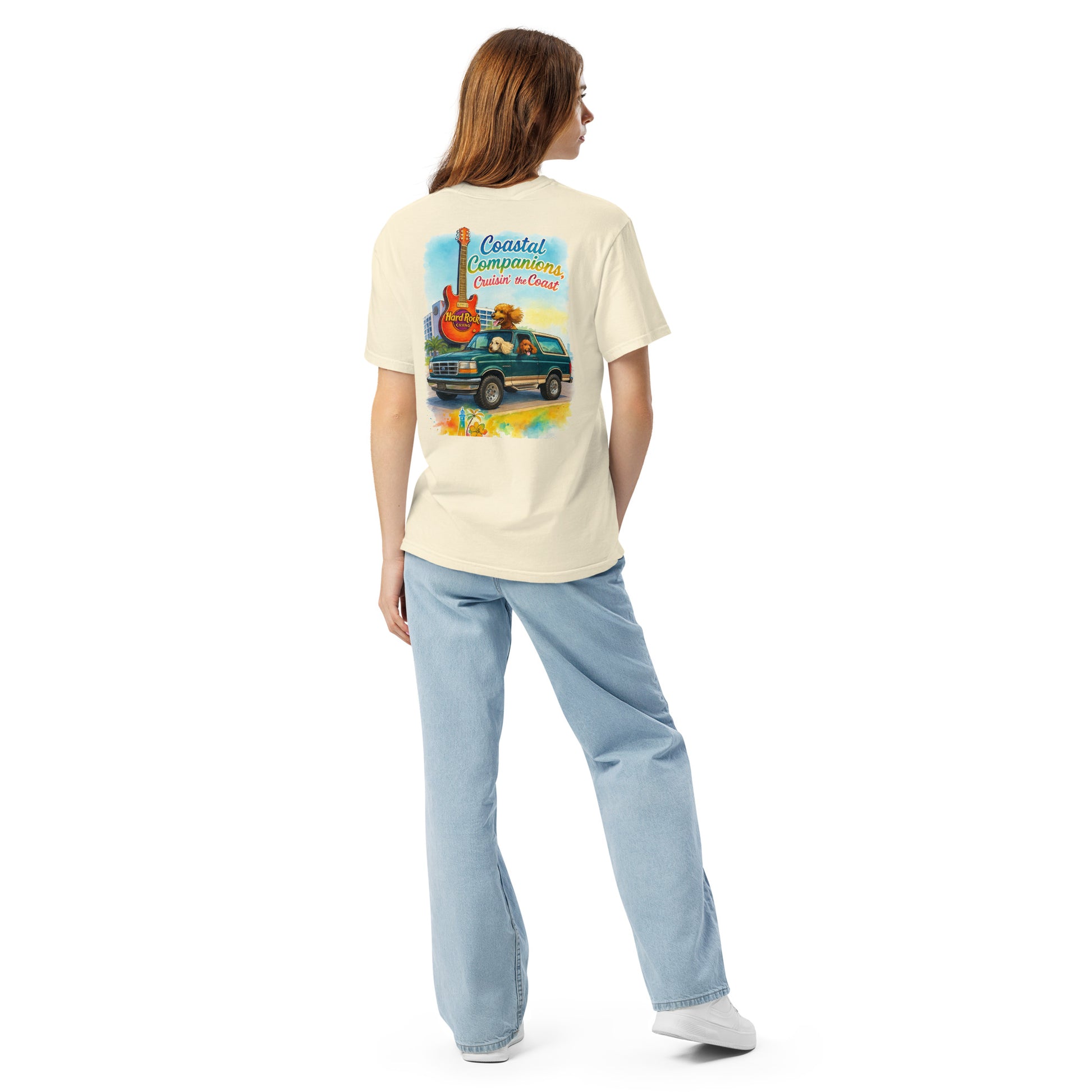 Back view of a woman wearing a cream Comfort Colors tee with a coastal design featuring a green Bronco, guitar, and dogs.