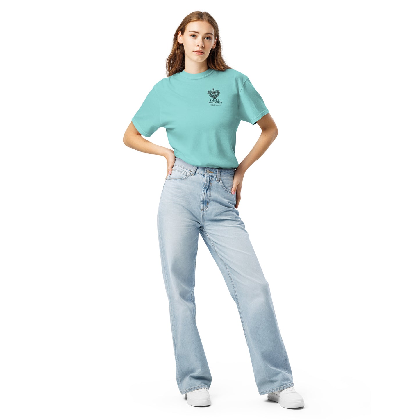 A woman models a teal Comfort Colors tee with Coastal Companions Hard Rock Bronco print, paired with light blue jeans and white sneakers.