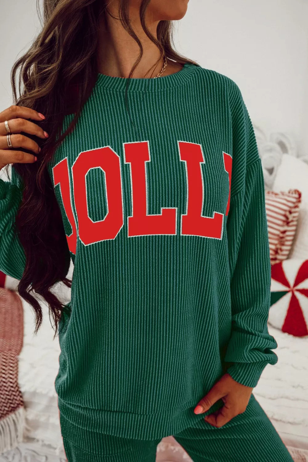 Woman wearing a green Jolly Christmas sweater and drawstring pants set.