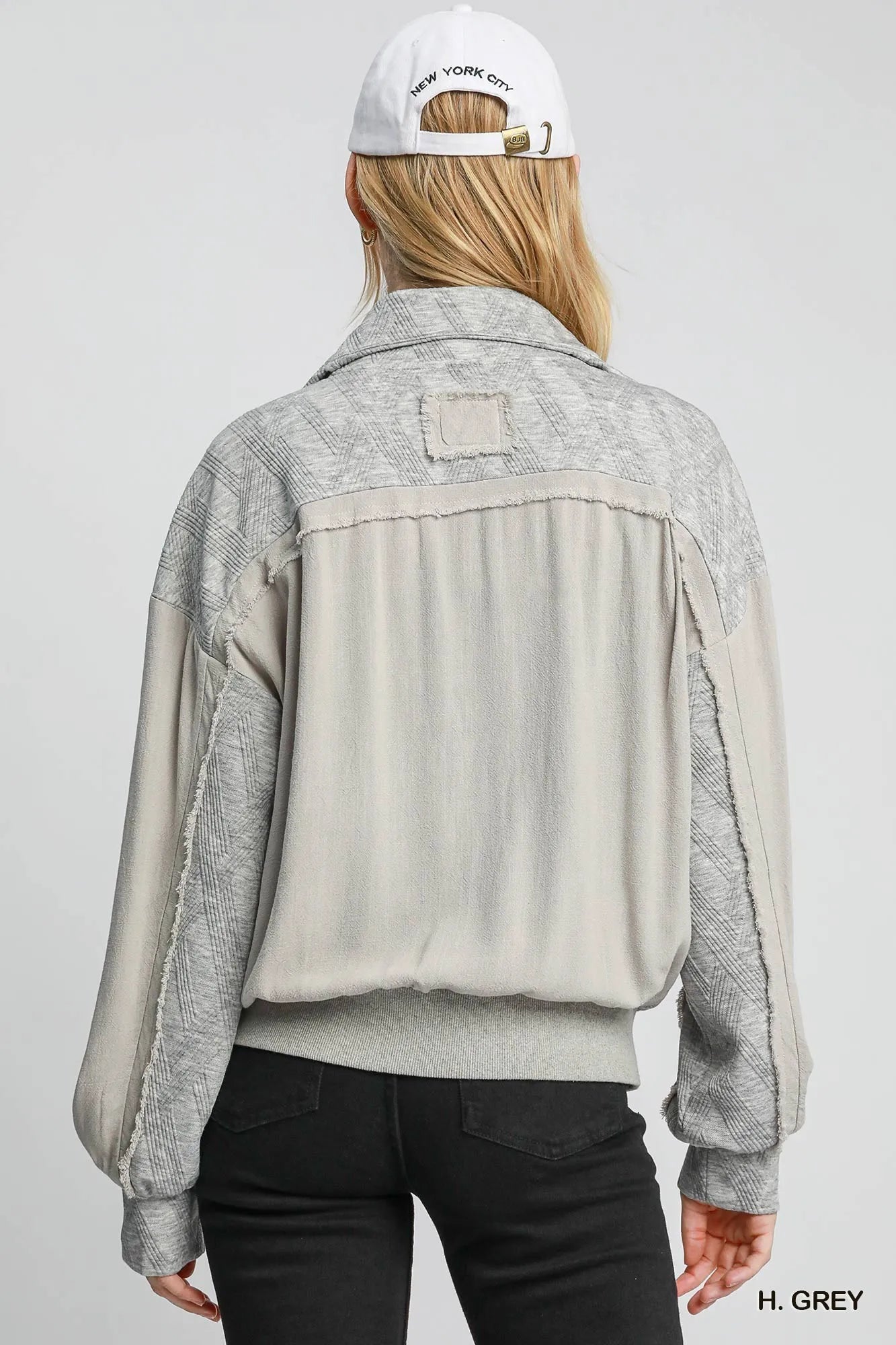 Rear view of gray two-way jacquard zip-up linen jacket on model with cap.
