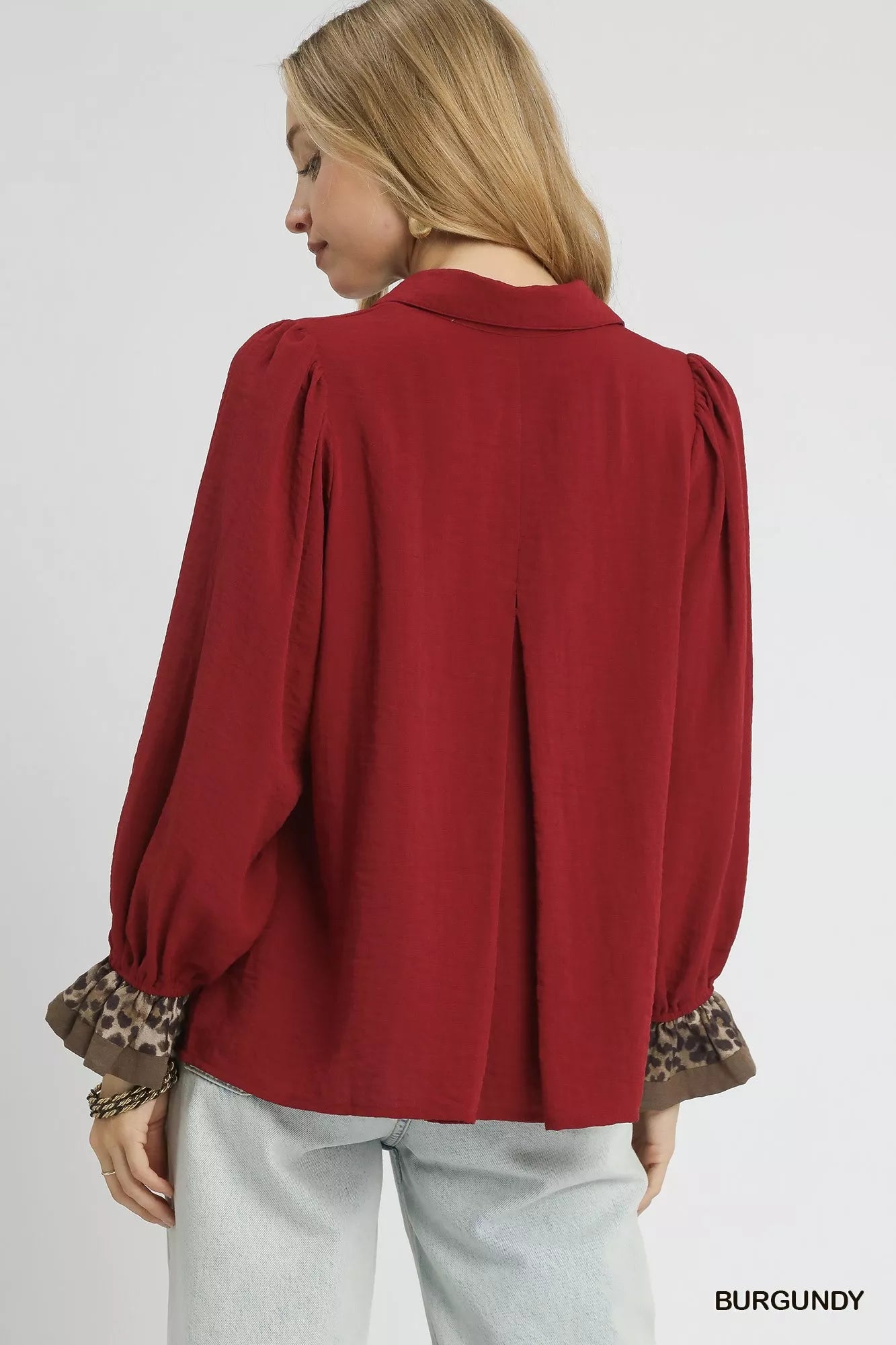 Rear view of burgundy Umgee half button blouse with leopard print trim on cuffs.