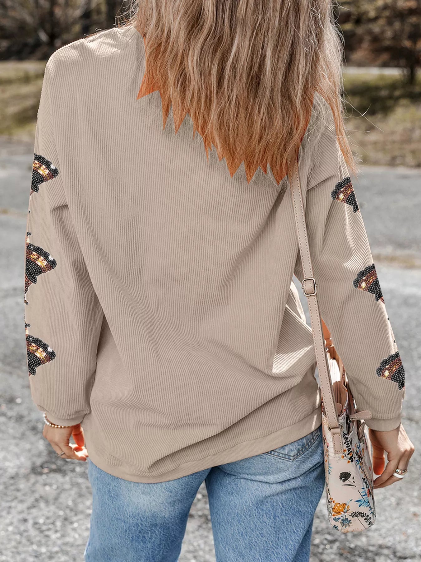 Rear view of a beige ribbed sweatshirt with turkey sequin embroidery on sleeves.