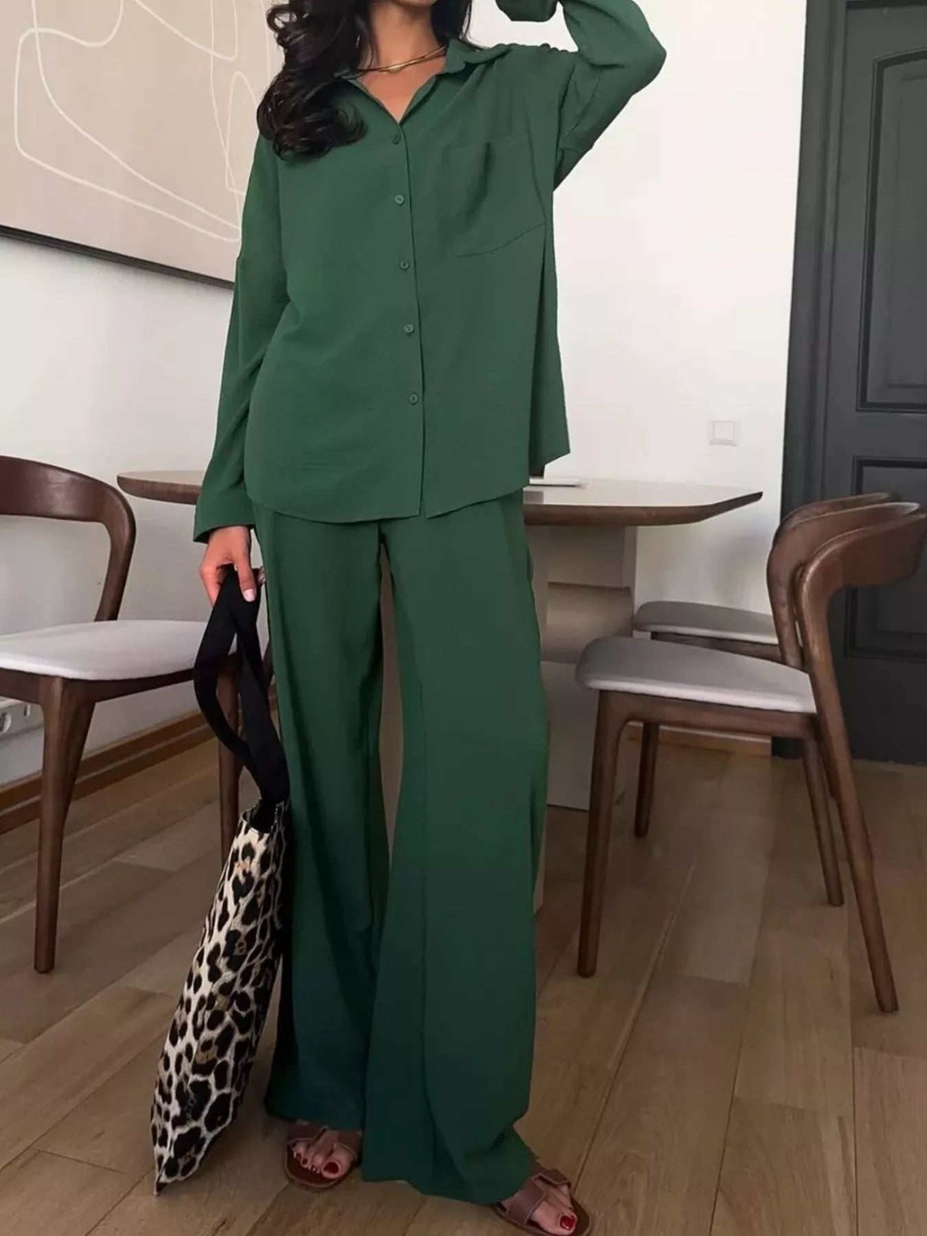 Woman wearing a green two-piece button-down shirt and wide-leg pants set with slight stretch.