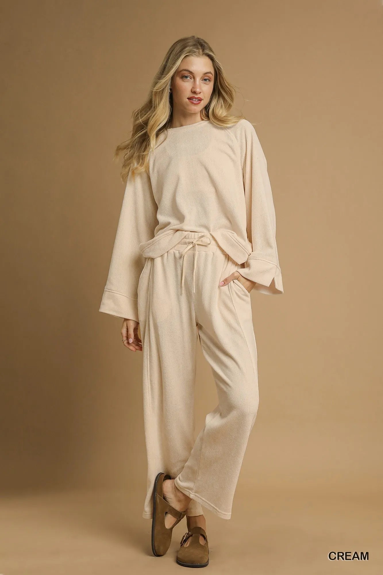 Cream-colored drawstring wide-leg pants with flowy fit on a model.