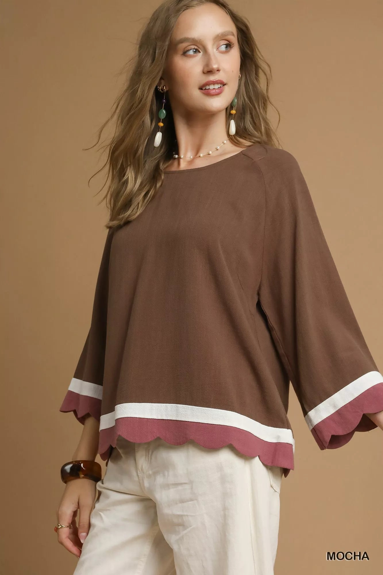 Woman wearing a brown scalloped hem color block linen blend top with white accents.