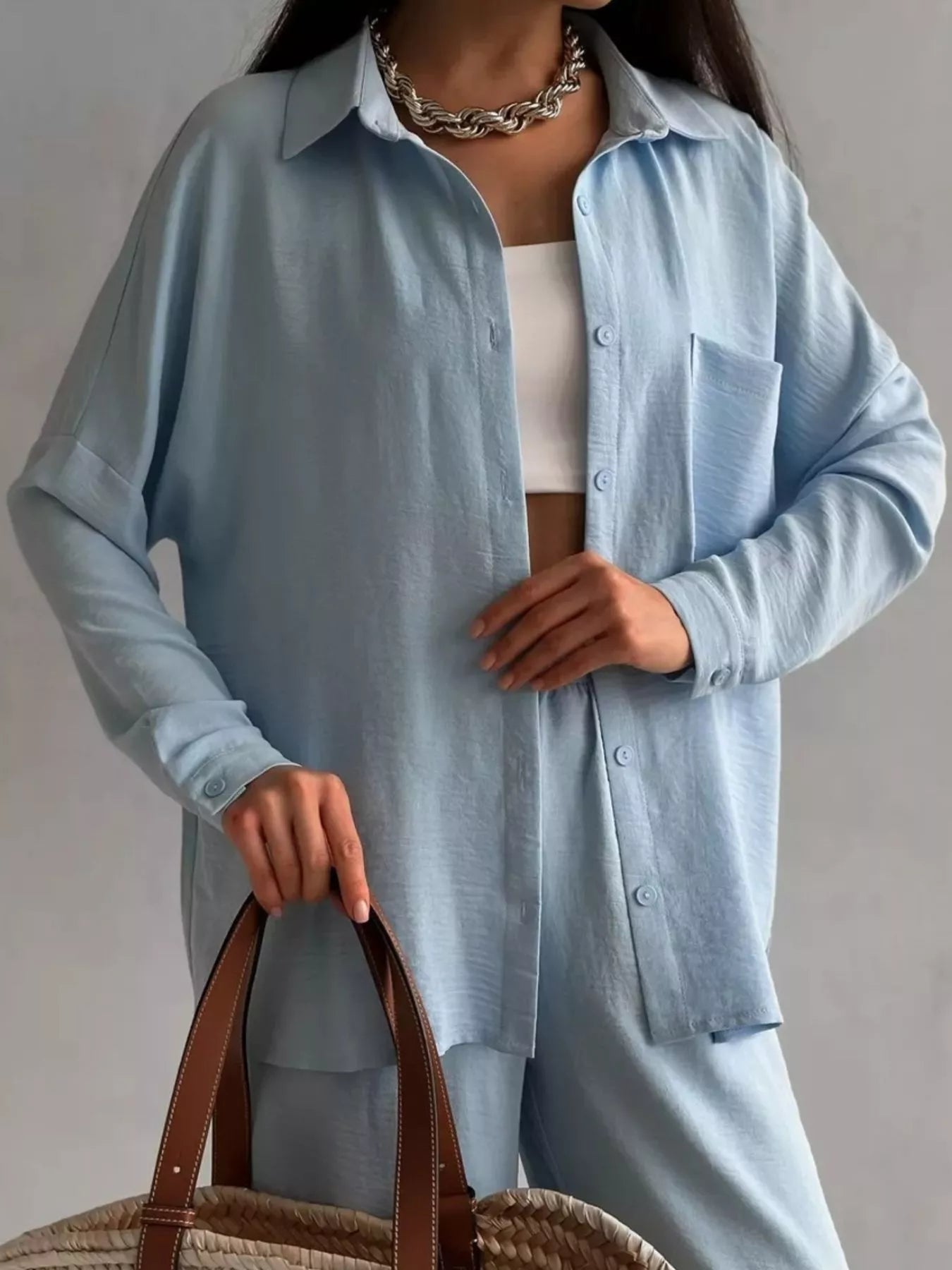 Woman modeling a light blue two-piece button-down shirt and pants set with pockets.