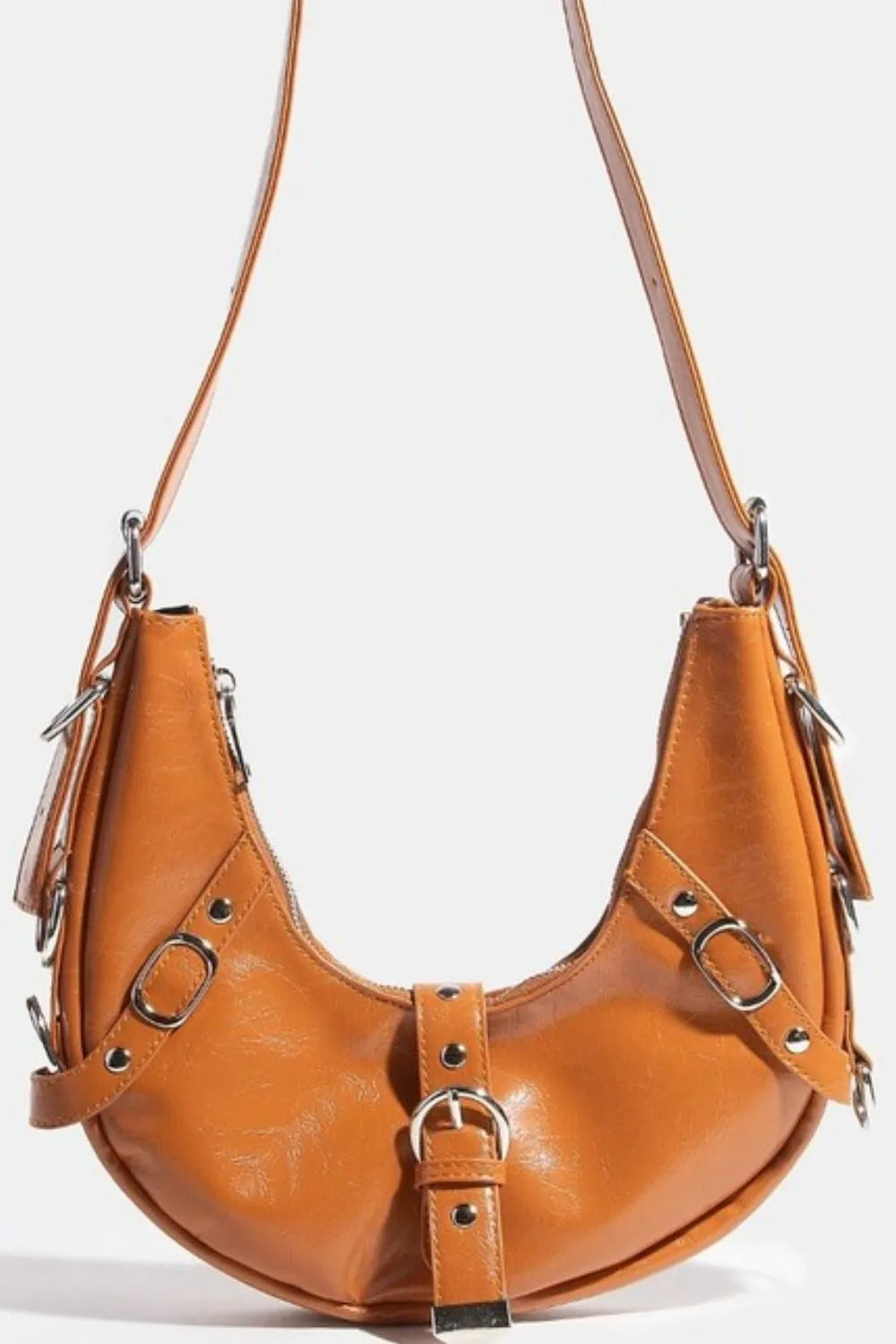 Cognac brown crescent leather shoulder bag with metal buckles and tassels.