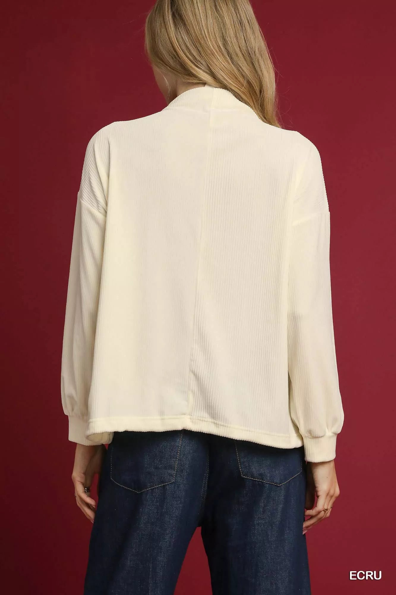 Rear view of a white ribbed knit top with drawstring hem on a model wearing jeans.