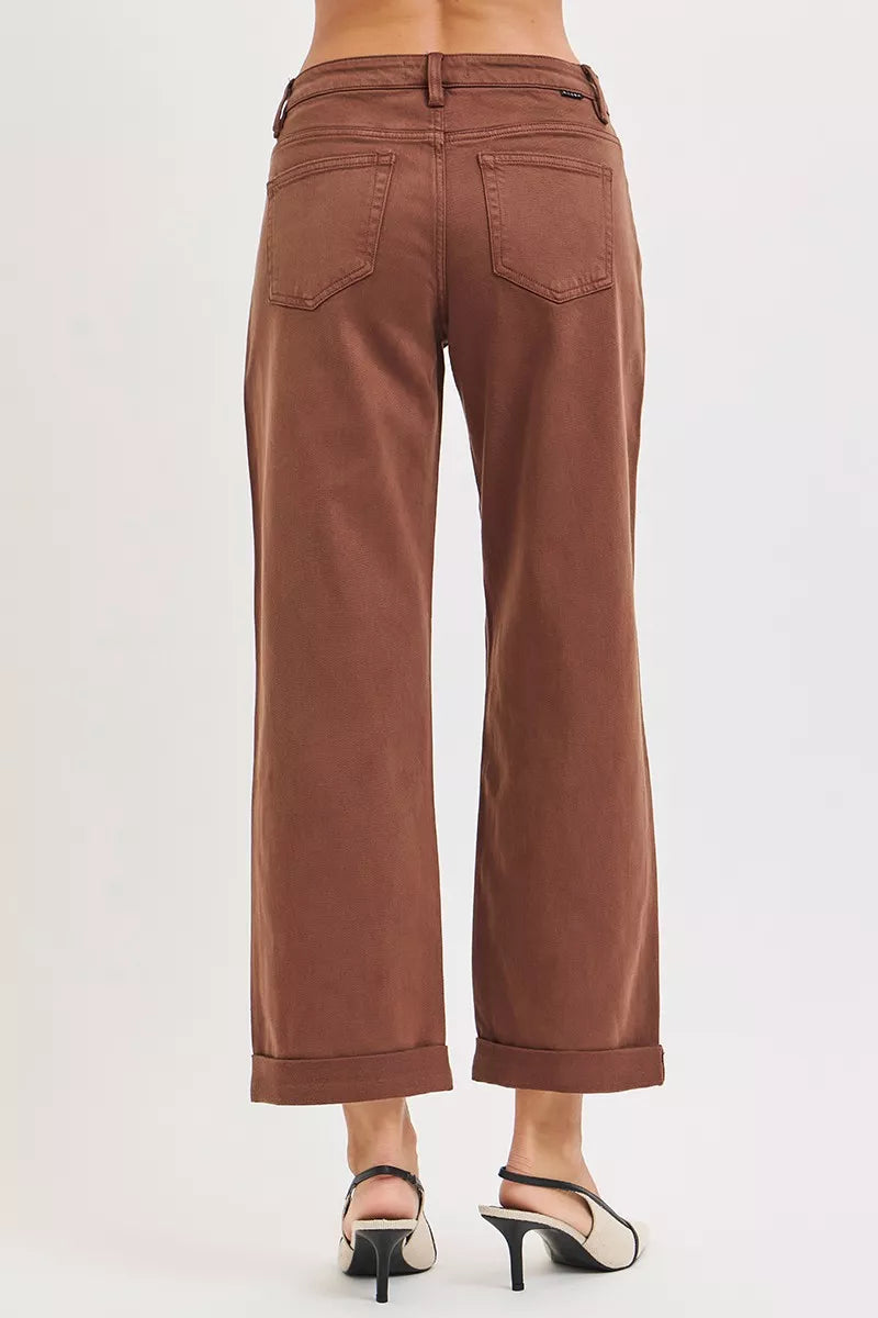 Rear view of brown wide-leg high-rise jeans on a plus-size model, with cuffed hems and black slingback heels.