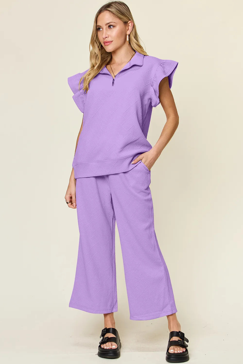 Woman modeling a purple textured ruffle short sleeve top and wide leg pants set.