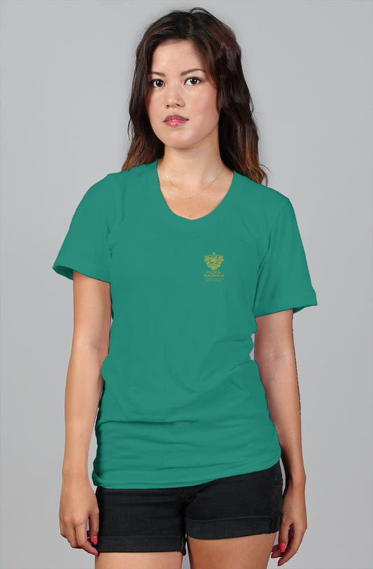 Woman modeling a relaxed-fit green cotton tee with gold emblem on chest, paired with black shorts.
