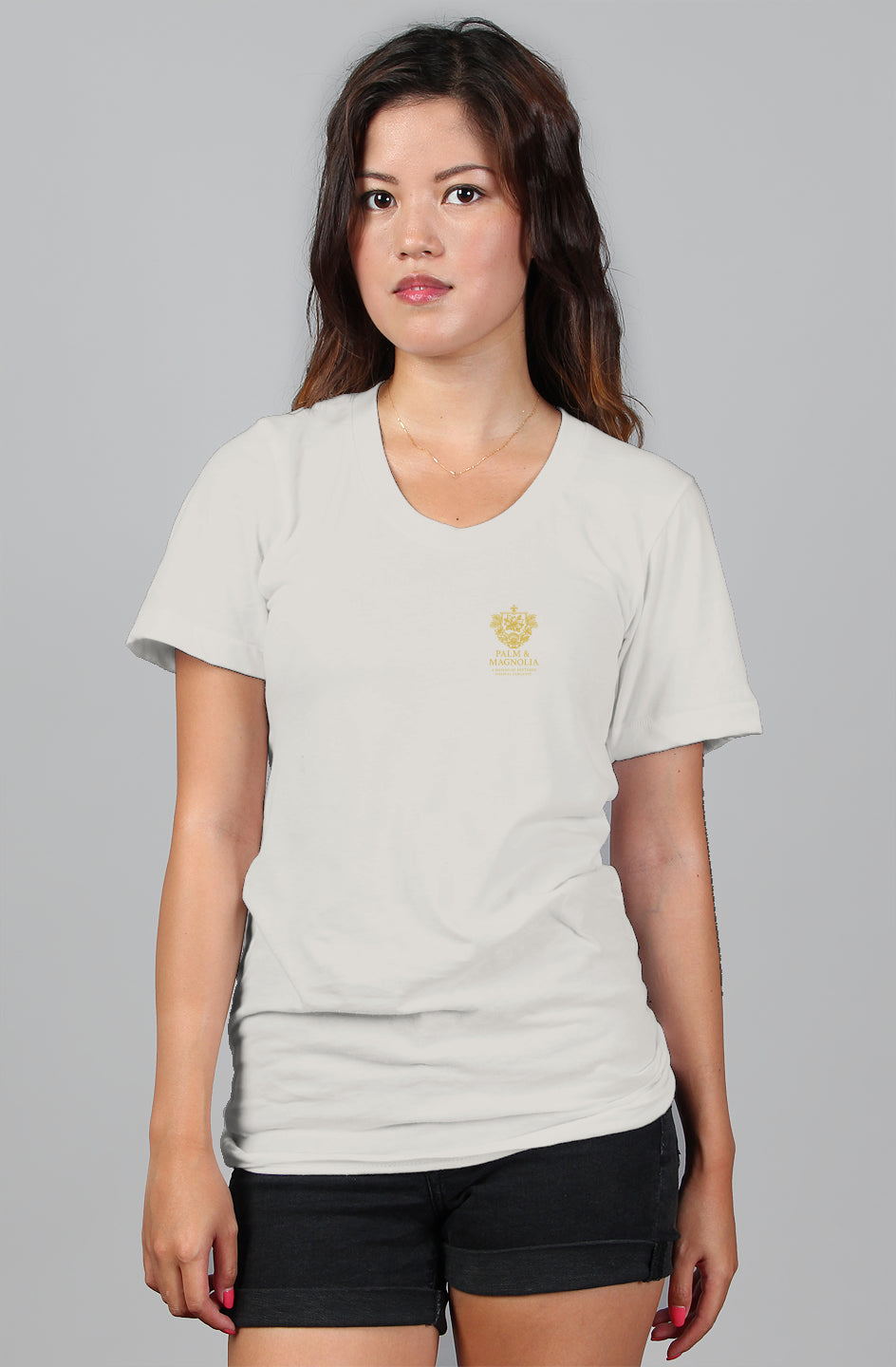 Woman in gray relaxed-fit women's cotton tee with gold crown emblem, paired with black shorts.