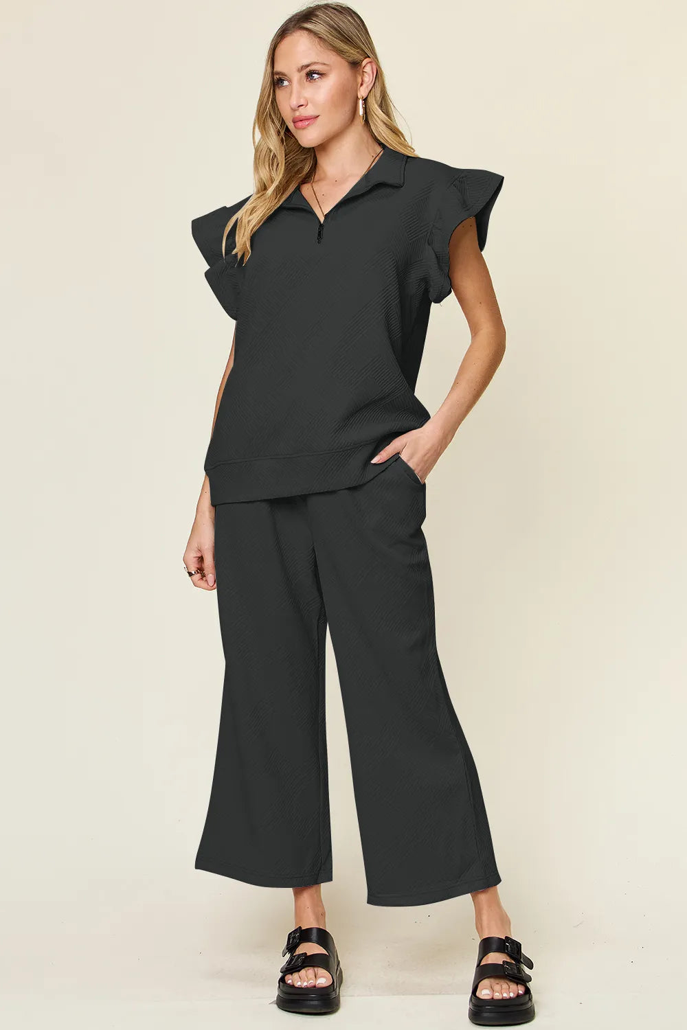 Woman modeling a textured ruffle short sleeve top and wide leg pants set in black.