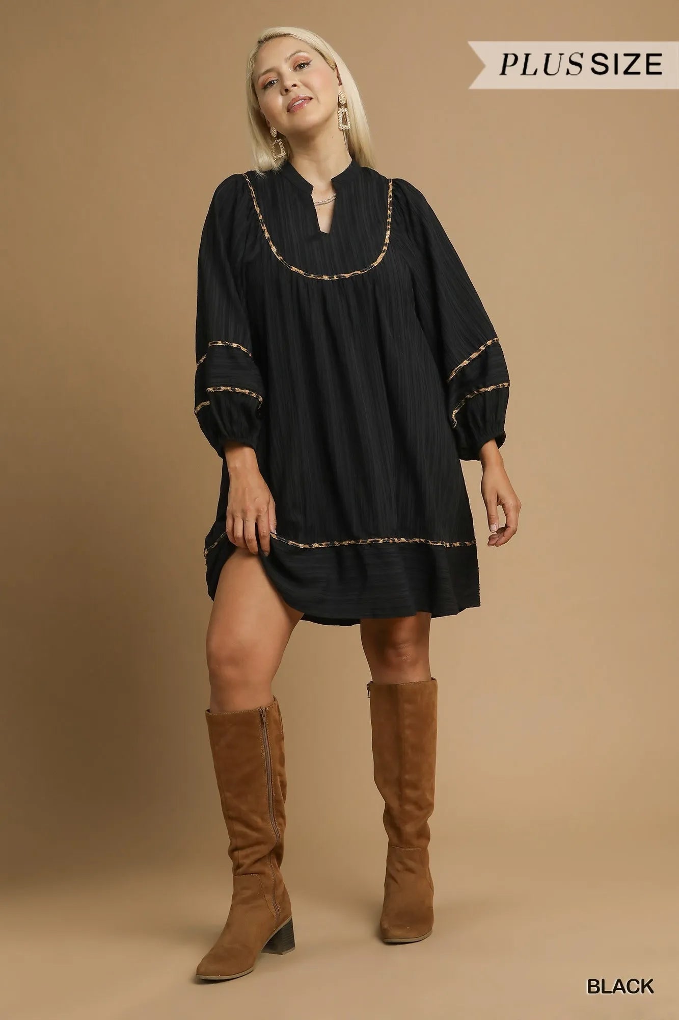 Plus size black textured babydoll dress with leopard trim, modeled with brown boots.