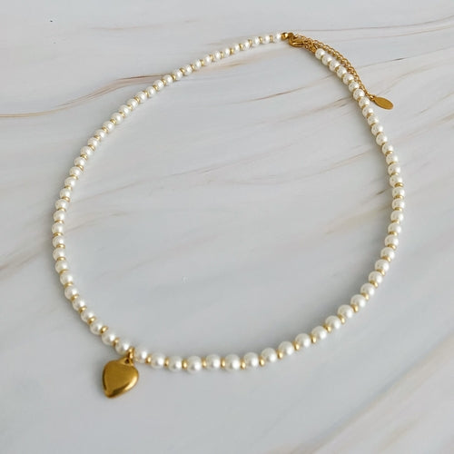 White pearl necklace with alternating gold bauble beads and gold heart pendant.