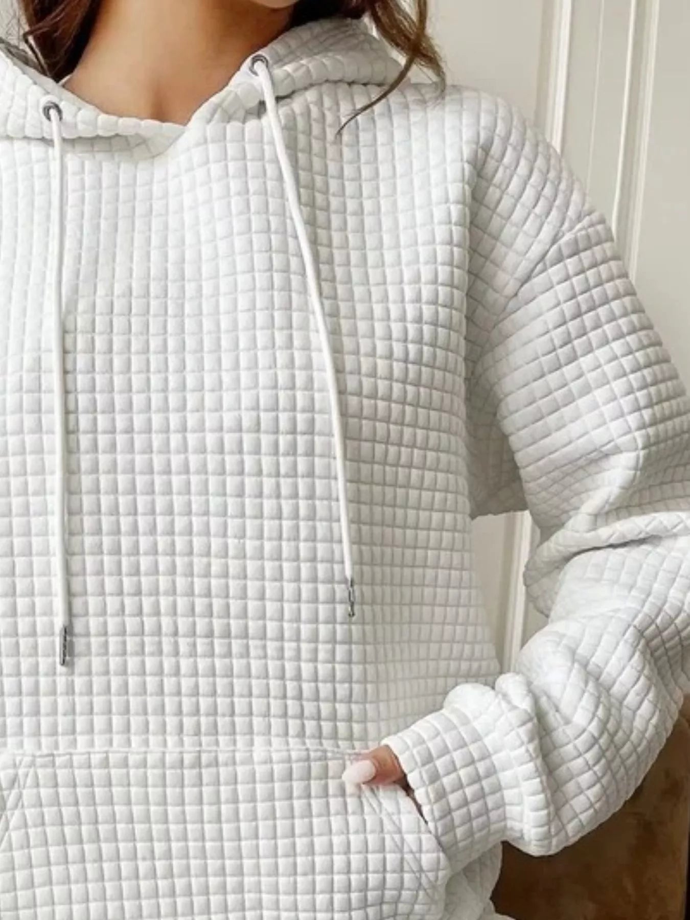 White waffle knit hoodie with drawstring hood and front pocket.