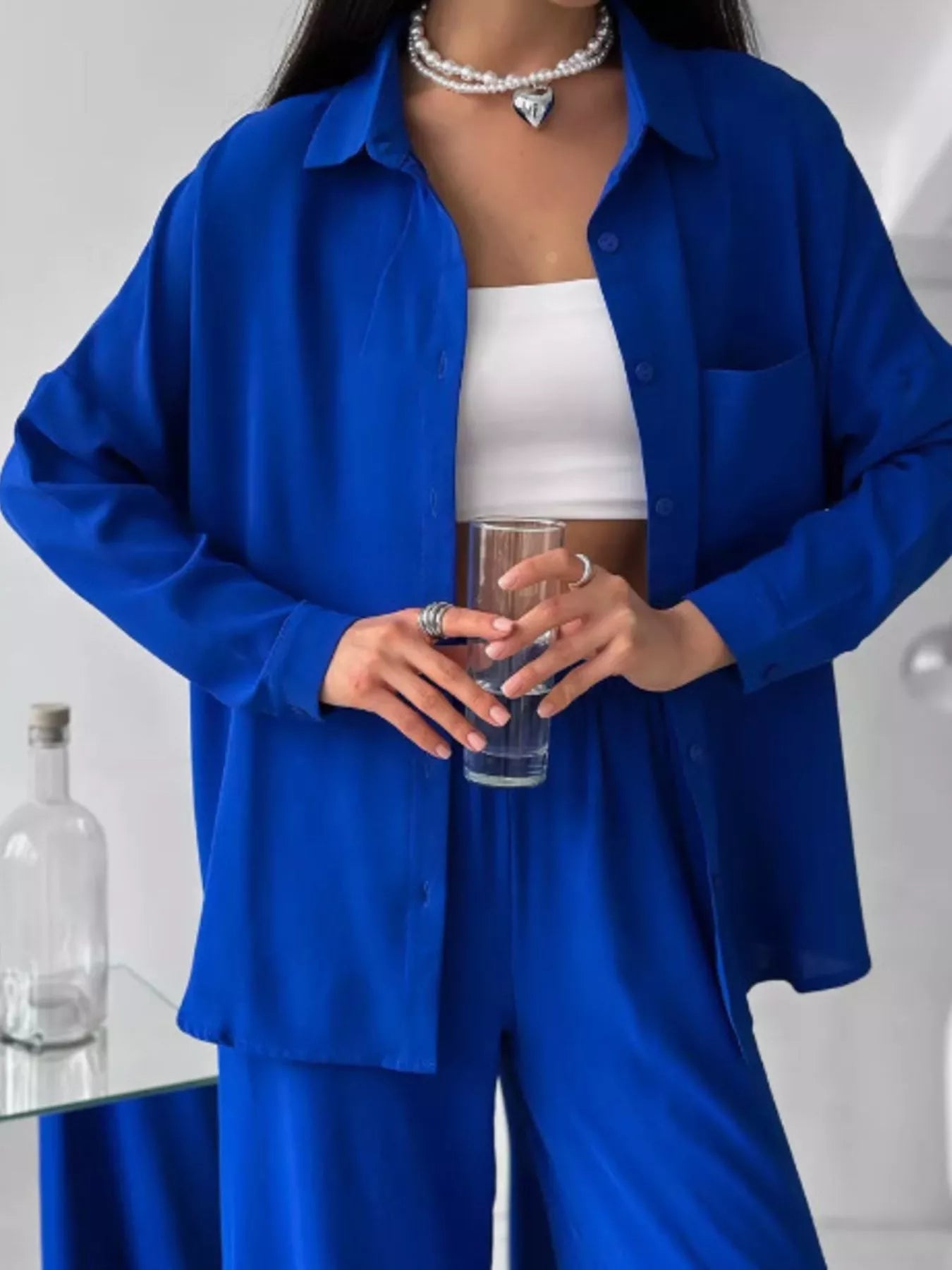 Woman wearing a blue two-piece button-down shirt and pants set with pockets and slight stretch.